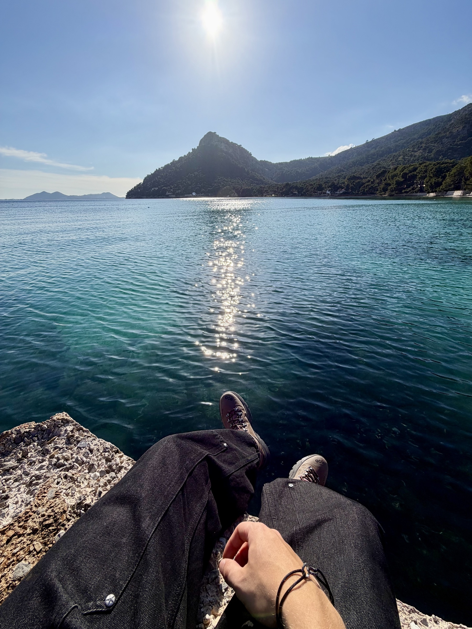 POV of feet on coastal rocks overlooking a Mallorca bay