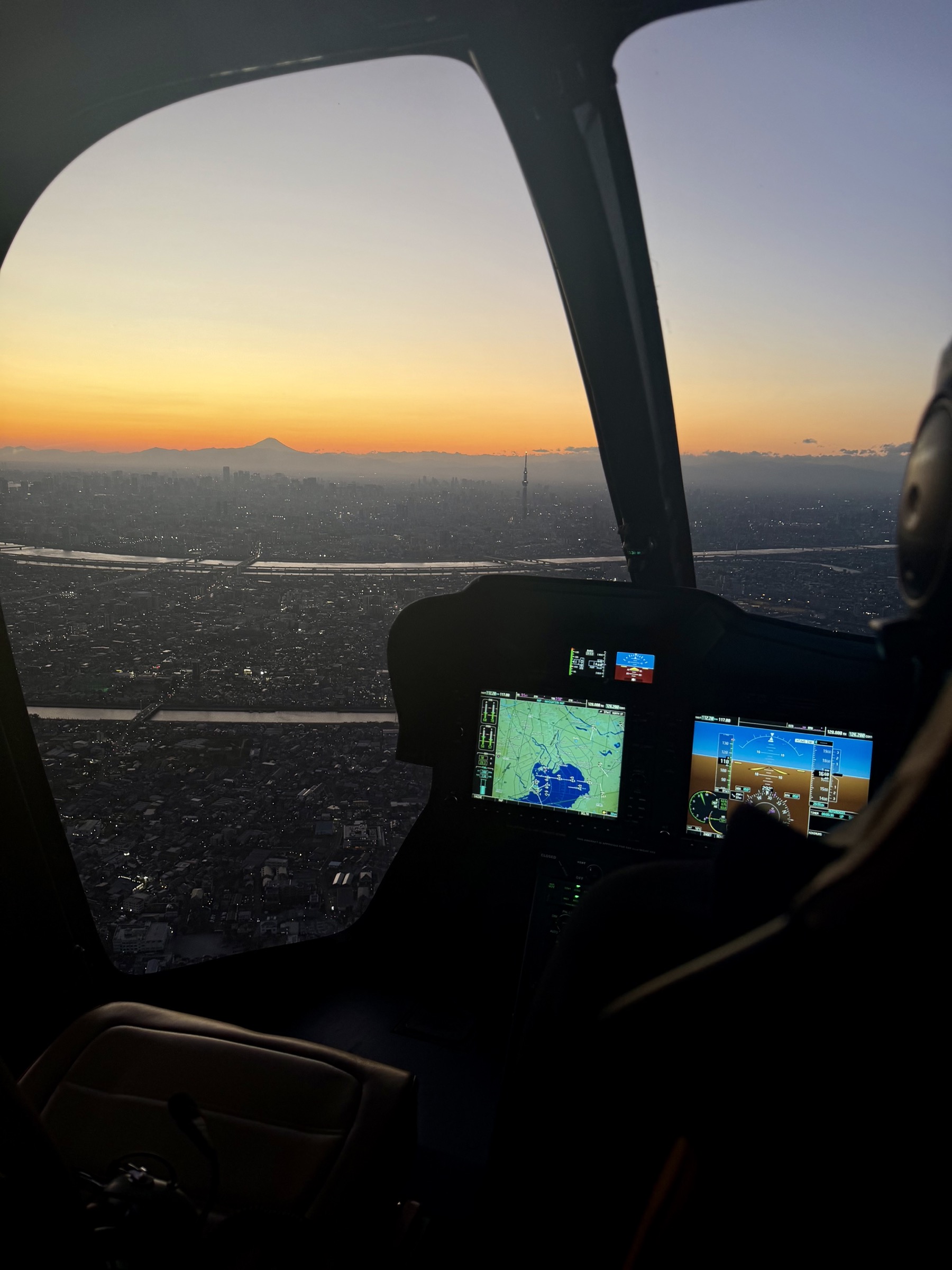Helicopter cockpit view over Tokyo with Mount Fuji on the horizon